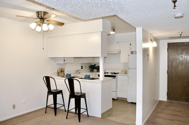 kitchen featuring ceiling fan, a breakfast bar, white appliances, kitchen peninsula, and white cabinetry