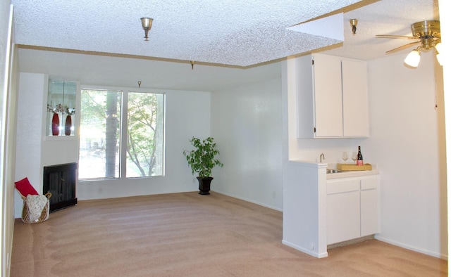 unfurnished living room with ceiling fan, light colored carpet, and a textured ceiling