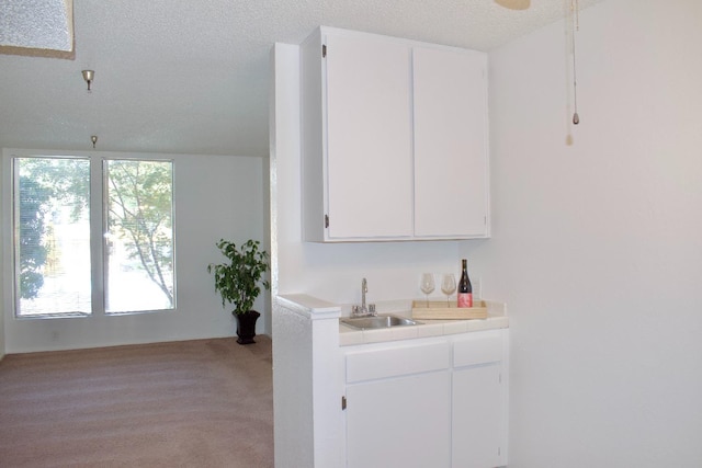 bar featuring light colored carpet, sink, a textured ceiling, and white cabinetry