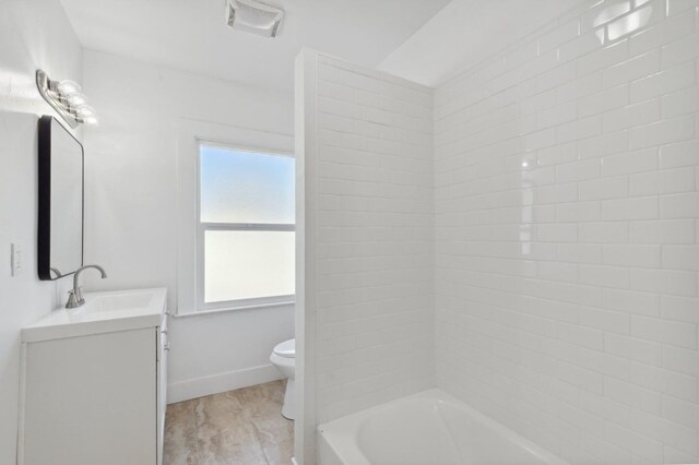 full bathroom with tiled shower / bath combo, wood-type flooring, toilet, and vanity