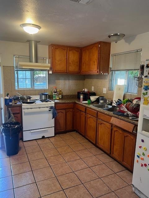 kitchen featuring tasteful backsplash, range hood, white appliances, and light tile patterned floors