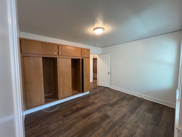 unfurnished bedroom with a closet and dark wood-type flooring