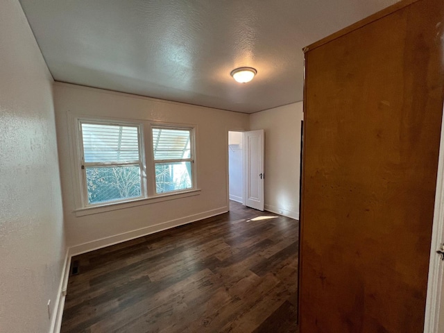 empty room with dark hardwood / wood-style flooring and a textured ceiling