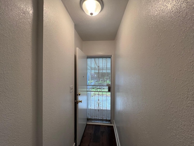 doorway with a textured ceiling and dark hardwood / wood-style floors