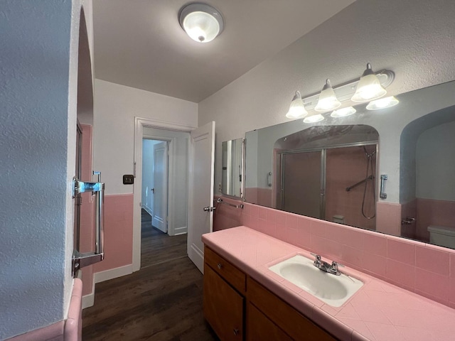 bathroom featuring hardwood / wood-style floors, vanity, backsplash, toilet, and a shower with shower door