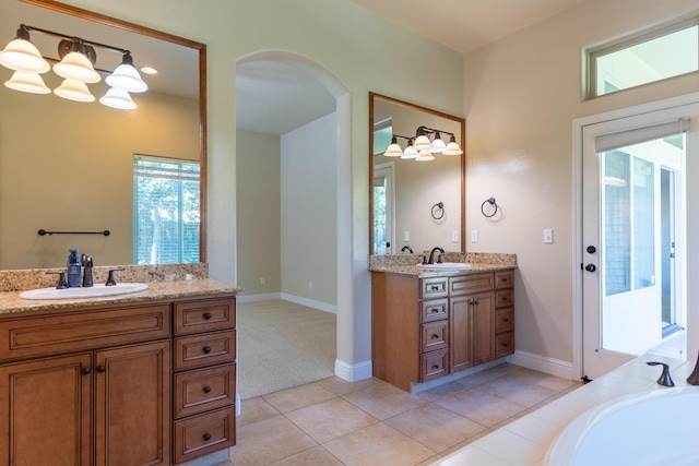 bathroom featuring a bathing tub, dual bowl vanity, and tile patterned floors