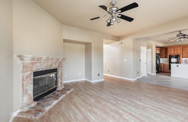 unfurnished living room featuring light wood-style floors, ceiling fan, baseboards, and a high end fireplace