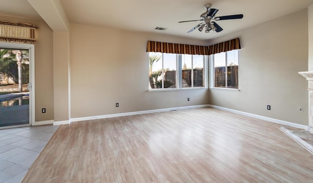 unfurnished room with a ceiling fan, visible vents, baseboards, and wood finished floors