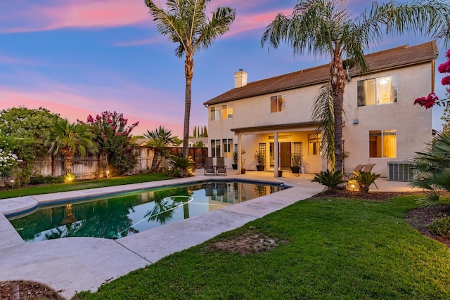 pool at dusk with a fenced in pool, a patio, a fenced backyard, a yard, and central AC