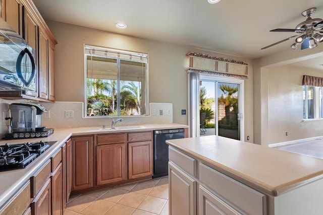 kitchen with tasteful backsplash, a healthy amount of sunlight, light tile patterned flooring, a sink, and black appliances