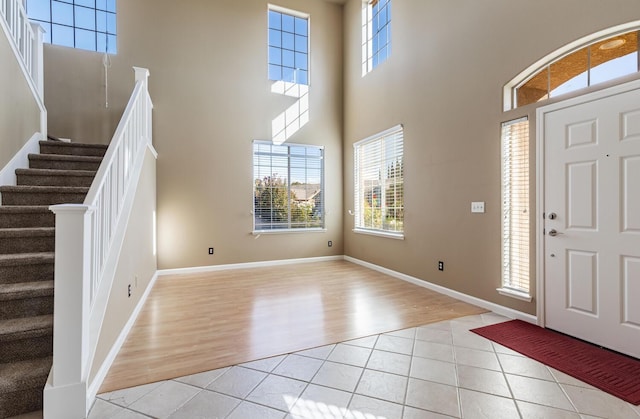 entryway with stairs, light tile patterned flooring, and baseboards