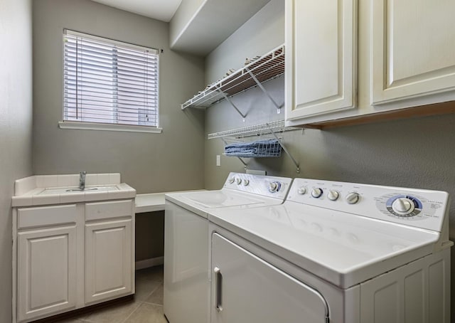 laundry room with cabinet space, light tile patterned floors, a sink, and washing machine and clothes dryer