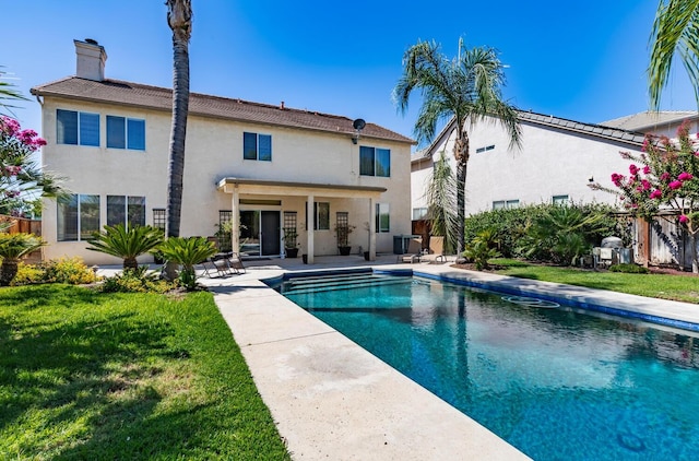 rear view of property featuring a fenced in pool, a yard, stucco siding, a patio area, and fence