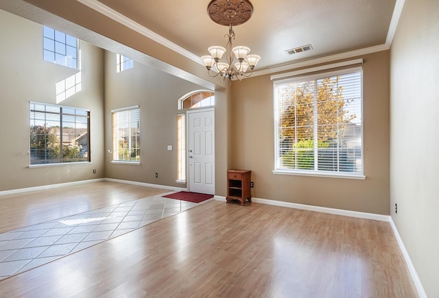 foyer entrance with crown molding, a notable chandelier, visible vents, wood finished floors, and baseboards