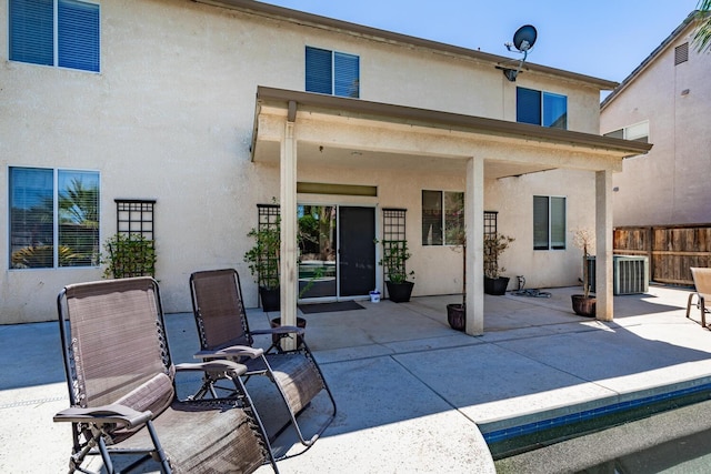 rear view of house featuring a patio, fence, and stucco siding