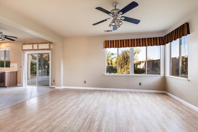 spare room with visible vents, ceiling fan, baseboards, and wood finished floors