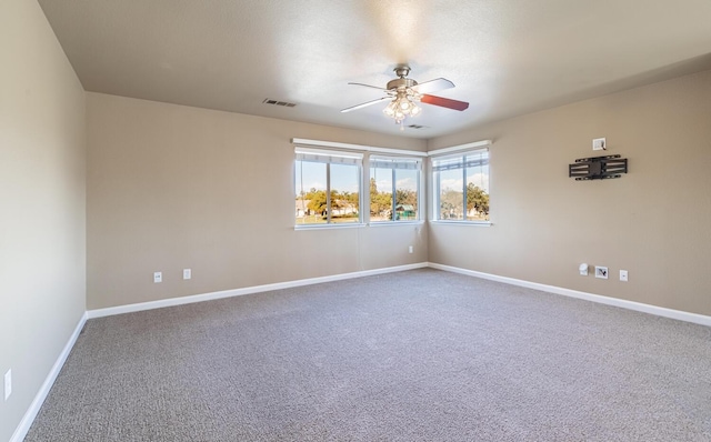 carpeted spare room with ceiling fan, visible vents, and baseboards