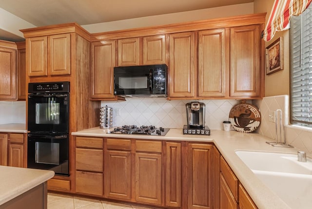 kitchen with light countertops, light tile patterned flooring, a sink, and black appliances