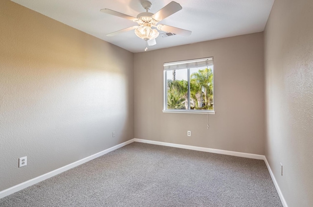 empty room with carpet floors, a ceiling fan, visible vents, and baseboards