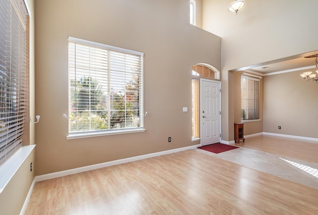 entrance foyer featuring baseboards, a high ceiling, a chandelier, and wood finished floors