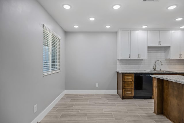 kitchen featuring white cabinetry, black dishwasher, sink, and decorative backsplash