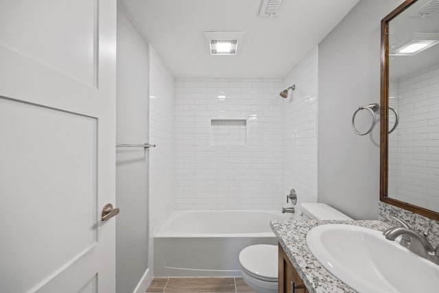 full bathroom with tiled shower / bath, toilet, tile patterned floors, and vanity