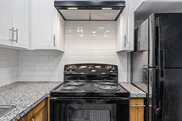 kitchen with backsplash, wall chimney exhaust hood, light stone countertops, black appliances, and white cabinets