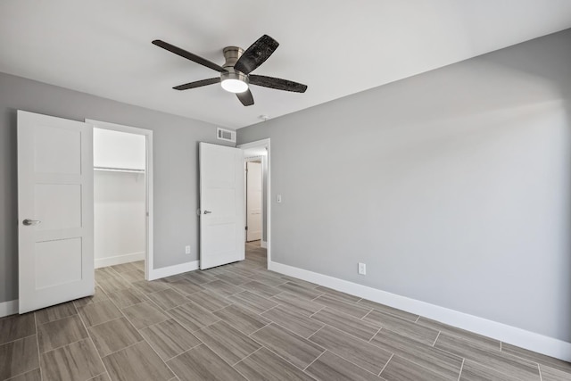 unfurnished bedroom with a walk in closet, ceiling fan, and a closet