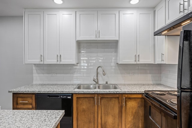 kitchen featuring sink, decorative backsplash, light stone counters, white cabinetry, and black appliances