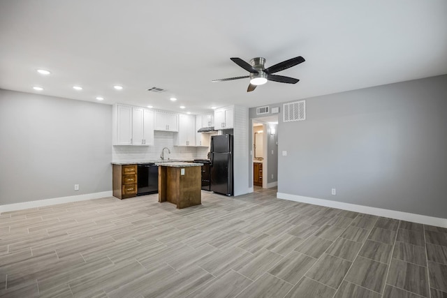 kitchen featuring backsplash, a kitchen island, ceiling fan, black appliances, and white cabinets