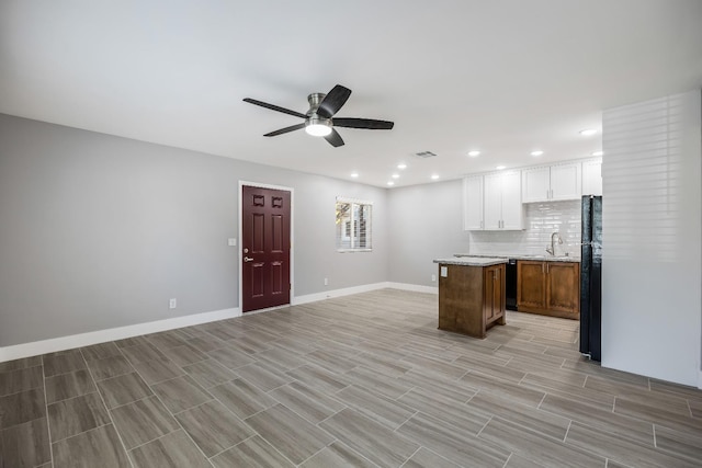 kitchen featuring ceiling fan, backsplash, white cabinets, black appliances, and a center island