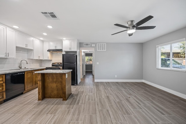 kitchen with white cabinetry, black appliances, light stone countertops, a kitchen island, and ceiling fan