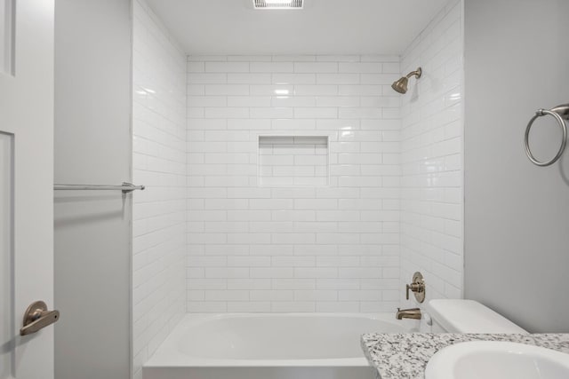 full bathroom featuring vanity, tiled shower / bath combo, and toilet