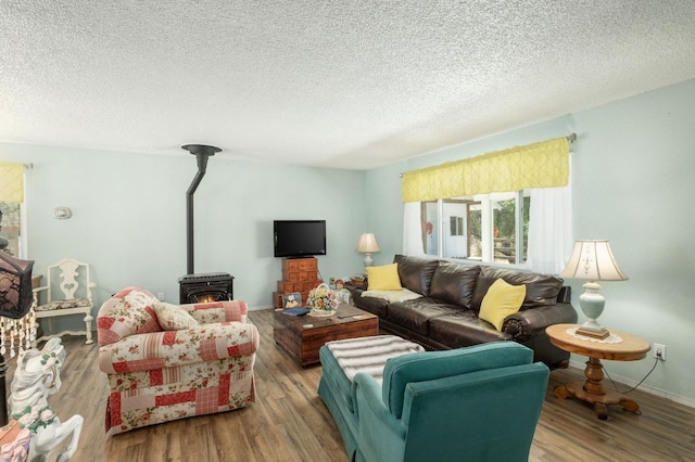 living room featuring a wood stove, a textured ceiling, baseboards, and wood finished floors