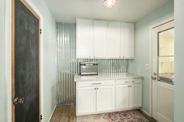 kitchen with light wood-style floors, white cabinetry, baseboards, and light stone countertops