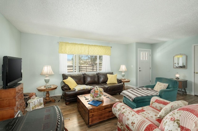 living room with a textured ceiling, baseboards, and wood finished floors