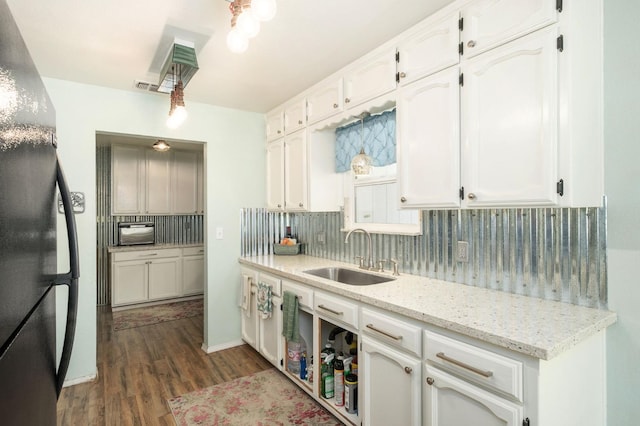 kitchen with tasteful backsplash, dark wood finished floors, a sink, freestanding refrigerator, and white cabinetry