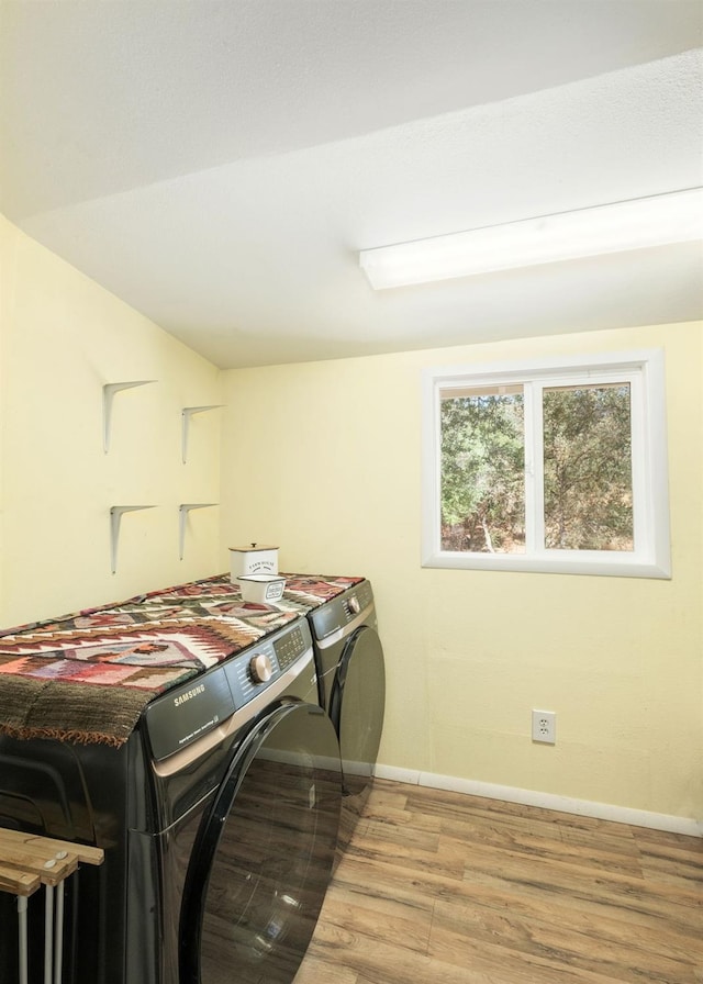 laundry room featuring laundry area, baseboards, wood finished floors, and separate washer and dryer