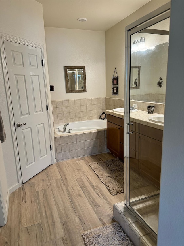 bathroom featuring independent shower and bath, hardwood / wood-style floors, and dual vanity