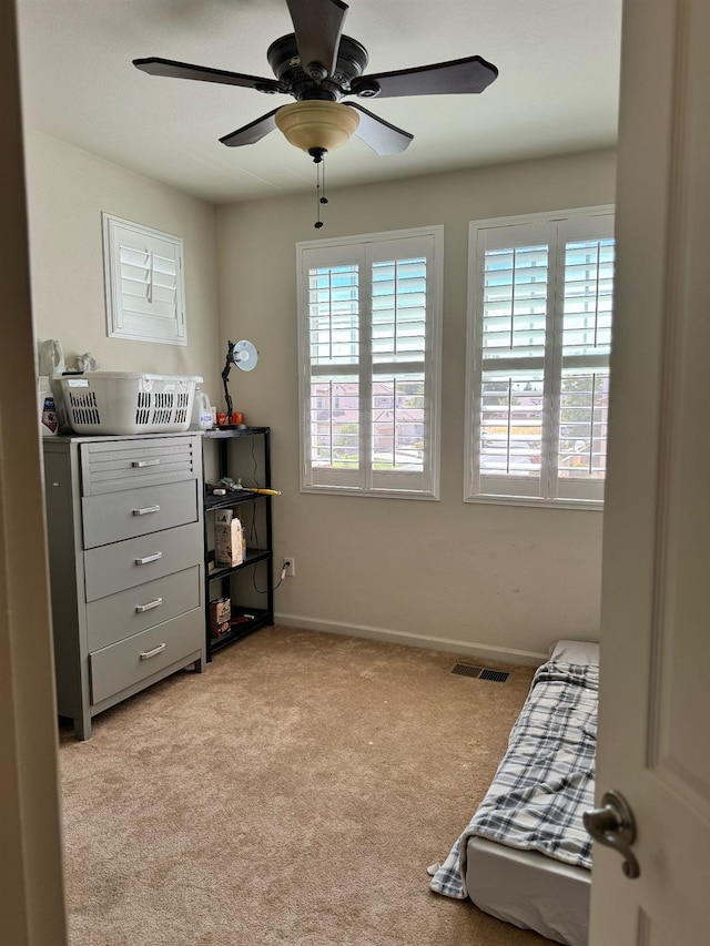 bedroom featuring ceiling fan, multiple windows, and light carpet