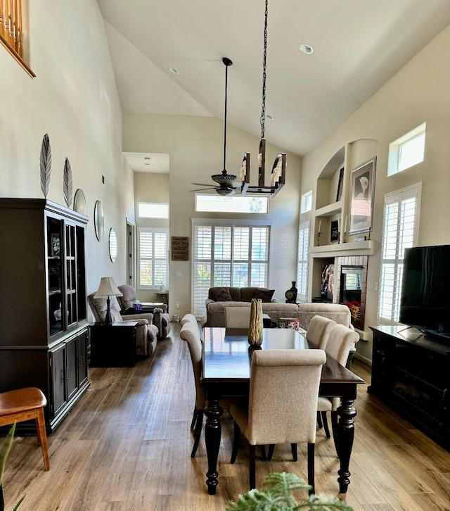 dining space with ceiling fan, high vaulted ceiling, and hardwood / wood-style flooring