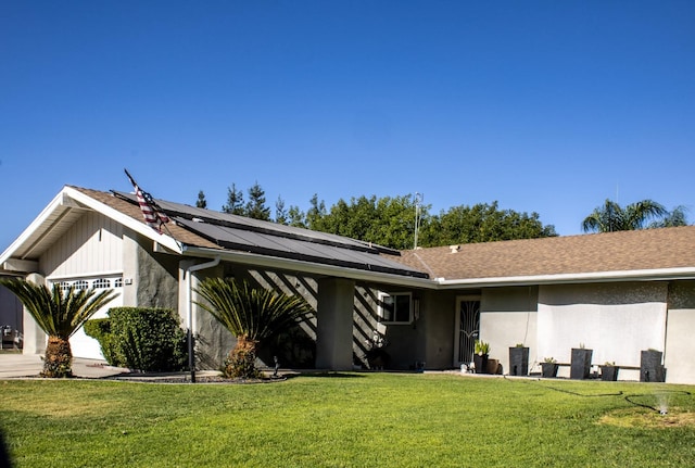 view of front of home featuring a garage, solar panels, and a front lawn