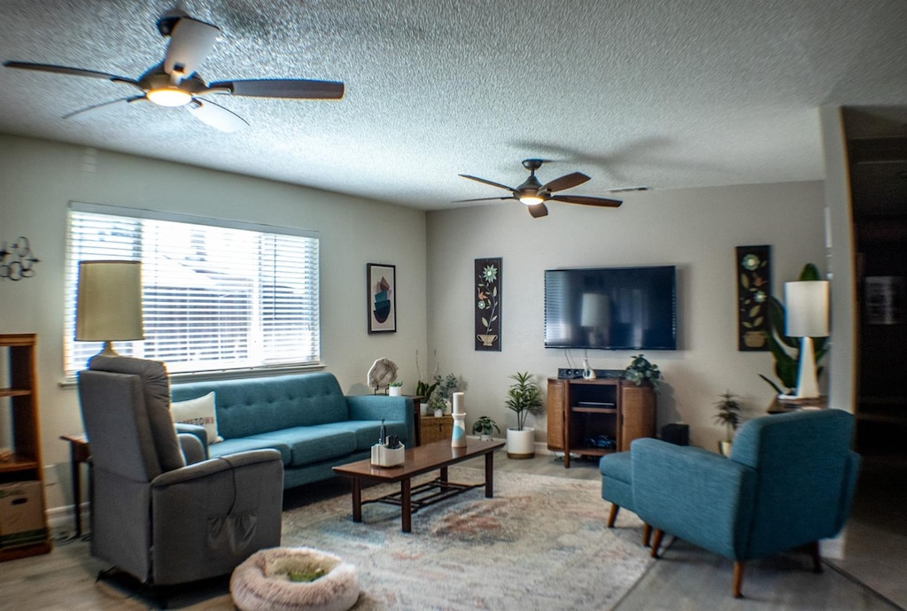 living room featuring a textured ceiling, ceiling fan, and light hardwood / wood-style flooring