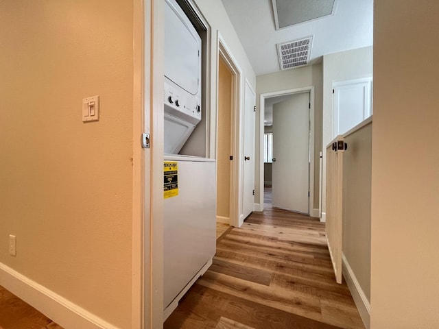 hall featuring light hardwood / wood-style flooring and stacked washer and dryer