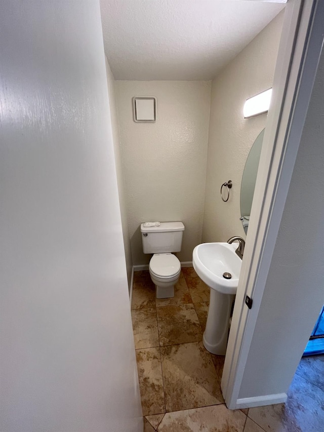 half bathroom featuring a sink, toilet, and baseboards