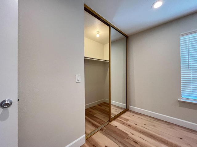 unfurnished bedroom with multiple windows, light hardwood / wood-style flooring, and a closet