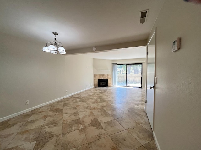 unfurnished living room with a tiled fireplace, light tile patterned floors, and a chandelier