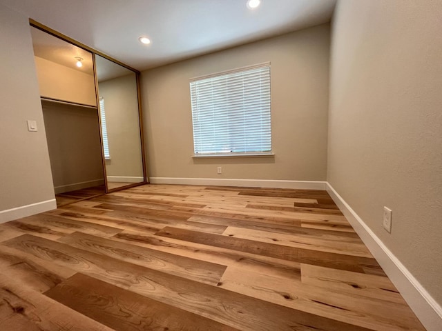 unfurnished bedroom featuring recessed lighting, a closet, baseboards, and wood finished floors