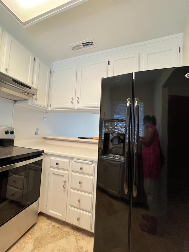 kitchen featuring black fridge, light tile patterned floors, white cabinetry, and stainless steel range with electric stovetop