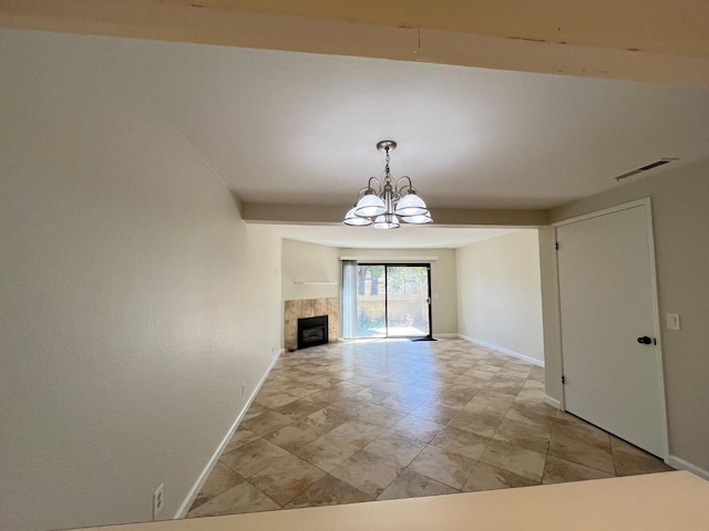 unfurnished dining area featuring baseboards, a tiled fireplace, visible vents, and a notable chandelier